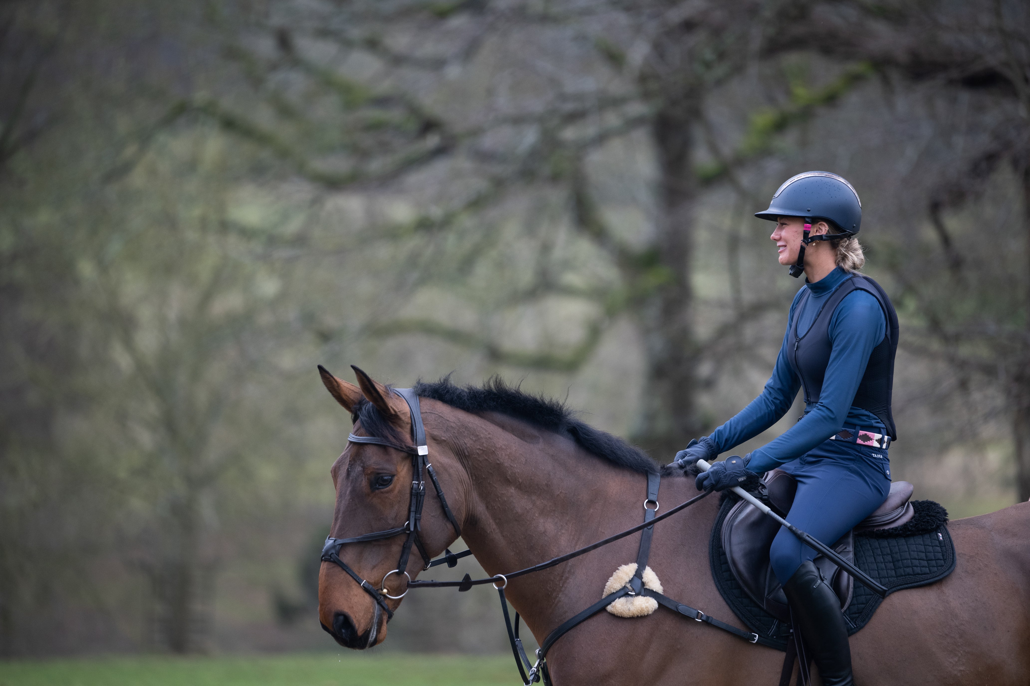 Rider jumping green and white jump wearing back protector